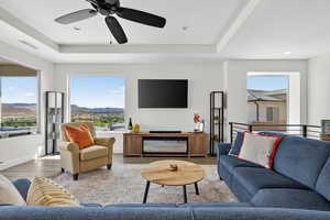 Living room featuring a tray ceiling, wood finished floors, a ceiling fan, and recessed lighting