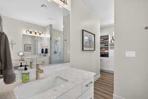 Full bathroom with a stall shower, vanity, a spacious closet, and light wood finished floors