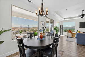 Dining room featuring a mountain view, wood finished floors, a ceiling fan, a raised ceiling, and suspended lighting