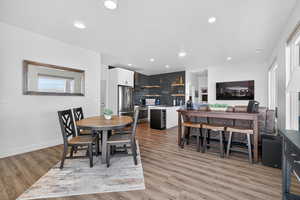 Dining space featuring light wood finished floors, recessed lighting, and beverage cooler