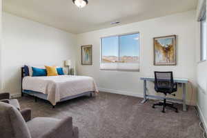 Carpeted bedroom with a desk and baseboards