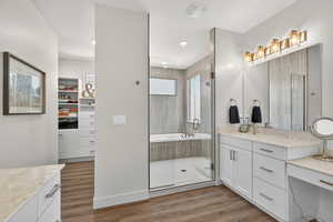 Full bathroom featuring vanity, light wood-style floors, a bath, and a stall shower