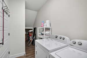 Laundry area featuring vaulted ceiling, dark wood-style flooring, and independent washer and dryer