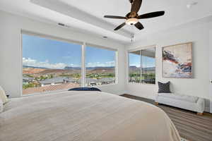 Bedroom with a mountain view, a tray ceiling, a ceiling fan, and dark wood finished floors