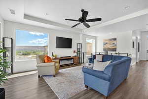 Living room featuring wood finished floors, ceiling fan, a raised ceiling, and recessed lighting