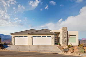 View of front of house with a mountain view, stucco siding, a garage, and driveway