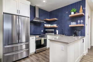 Kitchen featuring a peninsula, stainless steel appliances, open shelves, light wood-style floors, and recessed lighting