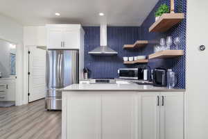 Kitchen with a peninsula, stainless steel appliances, open shelves, light stone countertops, and white cabinets