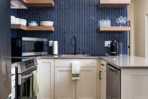 Kitchen featuring stainless steel appliances, dark stone counters, tasteful backsplash, open shelves, and white cabinetry
