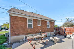 Rear view of property with brick siding, a gate, a fire pit, and a patio