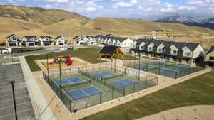 View of tennis court featuring a yard, a mountain view, a residential view, and a patio area