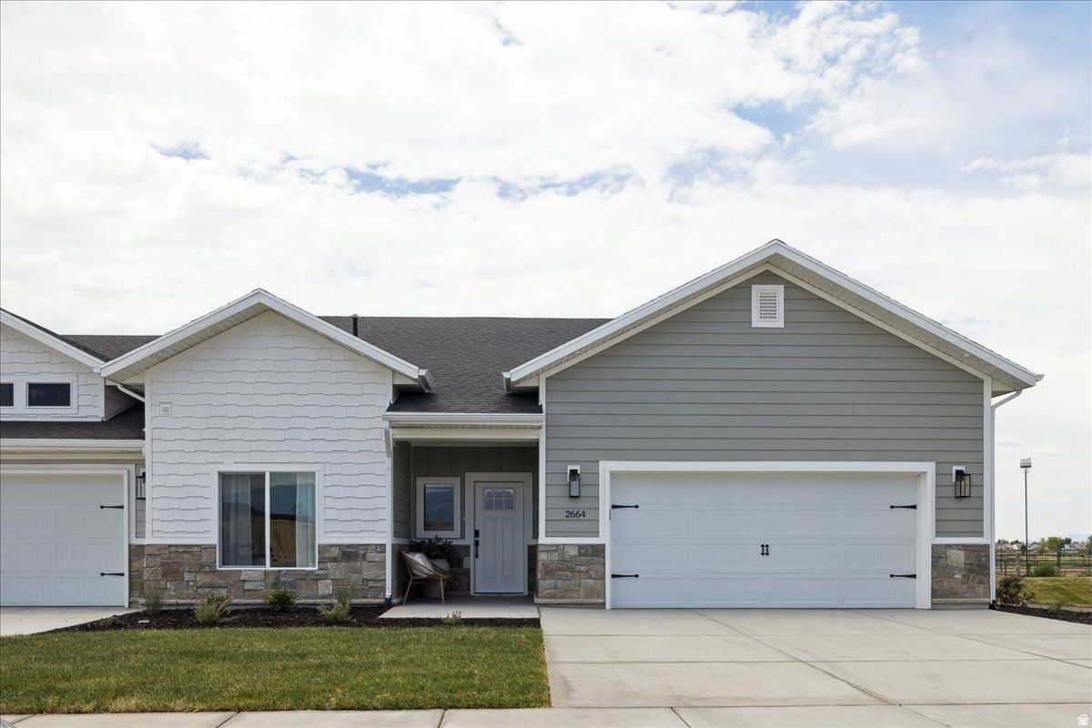 Contemporary exterior featuring light gray siding, white shake accents, and stone veneer detailing