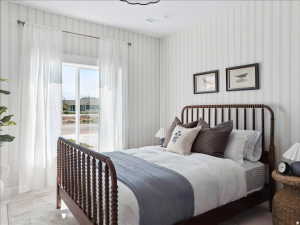 Bedroom featuring vertical striped wallpaper, white baseboards, and a large window with sheer white curtains