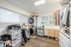 Laundry in Owner's bedroom area featuring stacked washer / drying machine and dark wood-type flooring