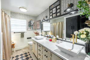Full bathroom featuring double vanity, plenty of natural light, tile walls, and curtained shower