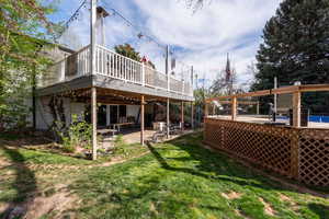 Rear view of property featuring a patio area, a wooden deck, and a lawn