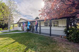 View of front of house with brick siding, a front lawn, and a patio area