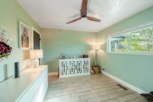 Sitting room featuring wood finish floors, a ceiling fan, and a textured ceiling