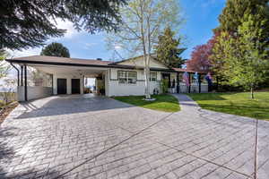 Ranch-style house with driveway, brick siding, a front yard, and an attached carport