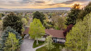 Aerial view of property and surrounding area featuring a mountainous background and a tree filled landscape