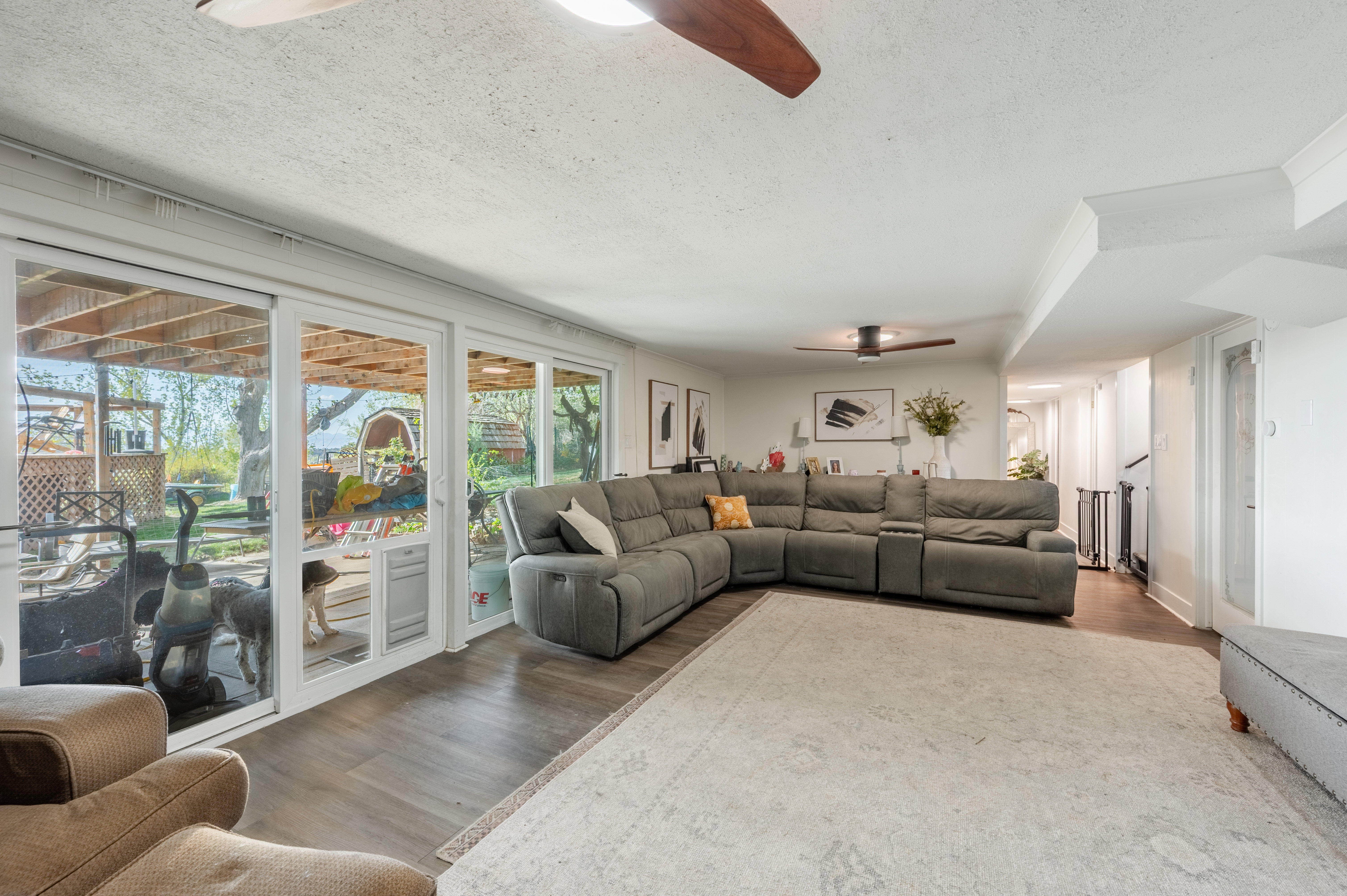 Living area with ceiling fan, a textured ceiling, and wood finished floors