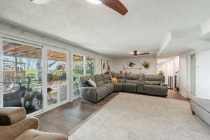 Living area with ceiling fan, a textured ceiling, and wood finished floors