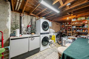 Laundry room featuring stacked washer and clothes dryer and concrete floors