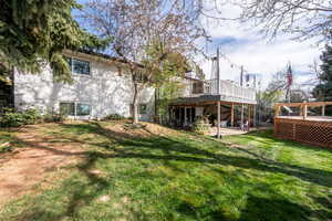 Rear view of property featuring a patio, a lawn, a deck, and brick siding