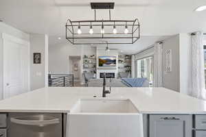Kitchen with a ceiling fan, dishwasher, a fireplace, lofted ceiling, and open floor plan