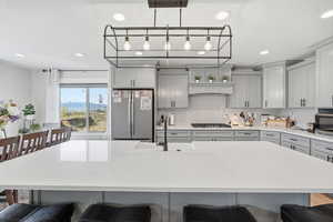 Kitchen featuring a breakfast bar area, gray cabinets, stainless steel appliances, light stone counters, and a mountain view