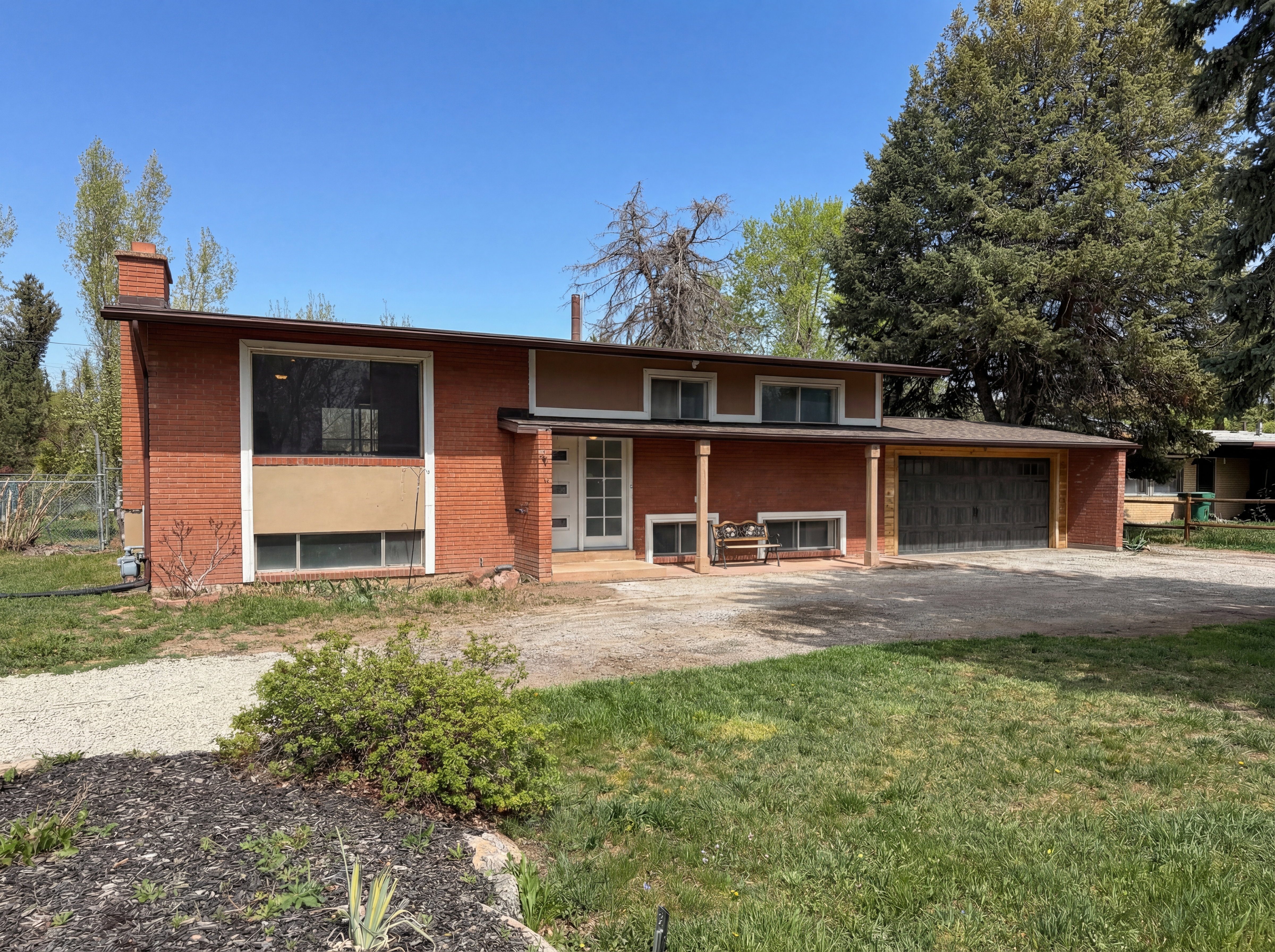 Bi-level home featuring an attached garage, a chimney, brick siding, and driveway