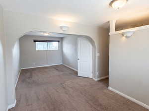 Unfurnished room with arched walkways and carpet flooring