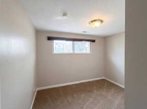 Unfurnished room featuring baseboards and light carpet