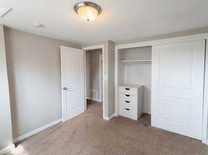 Unfurnished bedroom with light carpet and a closet