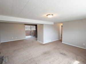 Spare room featuring light carpet and baseboards