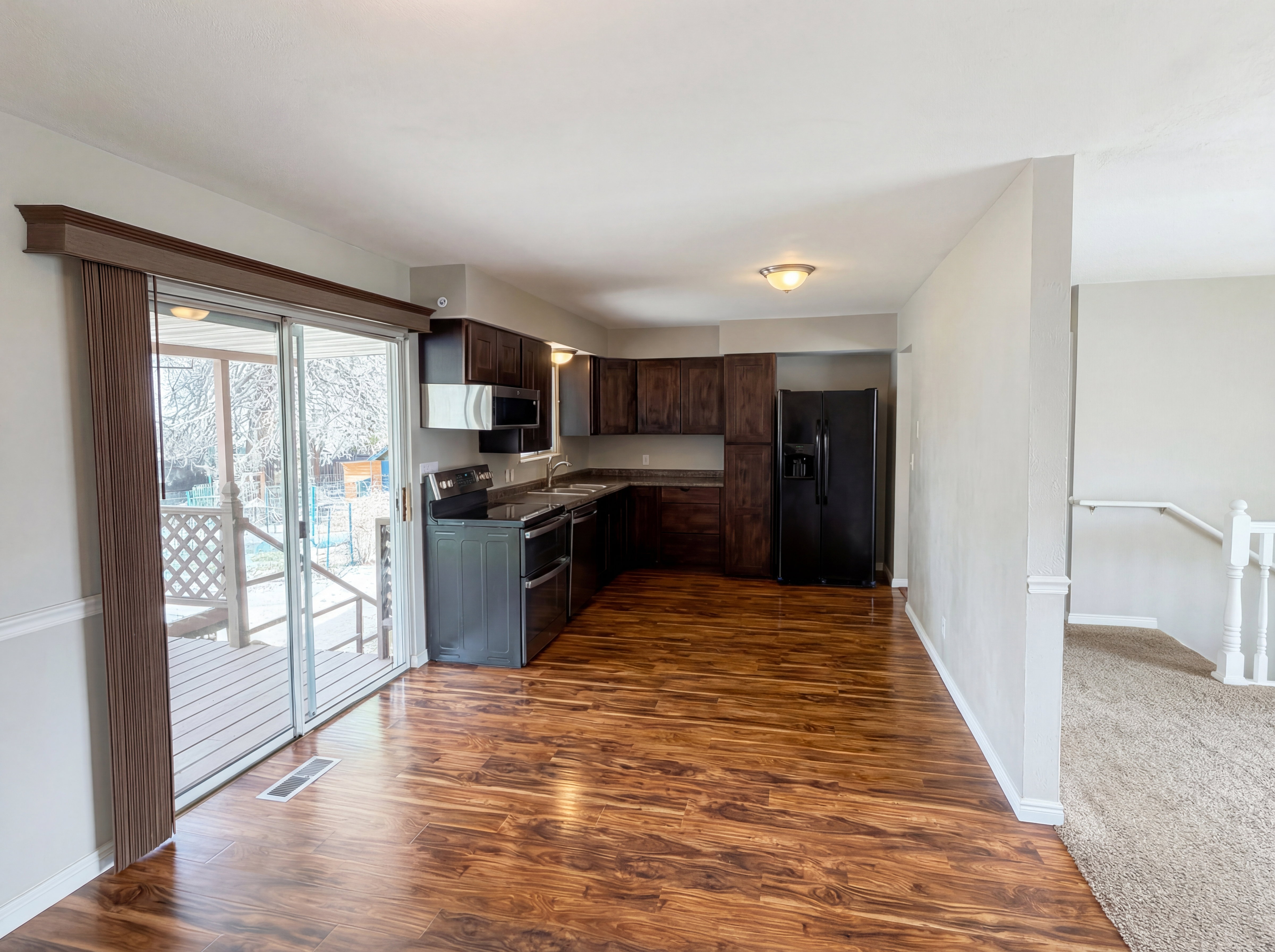 Kitchen featuring dark wood finish cabinets, stainless steel appliances, dark wood-style flooring, and dark countertops