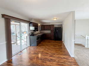 Kitchen featuring dark wood finish cabinets, stainless steel appliances, dark wood-style flooring, and dark countertops