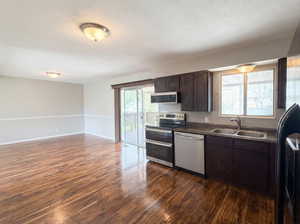 Kitchen featuring dark wood finish cabinetry, stainless steel appliances, dark wood-style flooring, and open floor plan