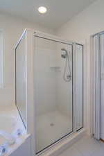 Bathroom with a garden tub, light tile patterned flooring, and a shower stall