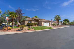 View of front facade featuring a garage, concrete driveway, stucco siding, a residential view, and a front yard
