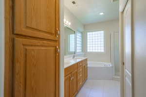 Full bathroom with double vanity, a stall shower, light tile patterned floors, and a bath