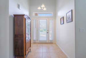 Entryway featuring a chandelier, light tile patterned floors, and a high ceiling