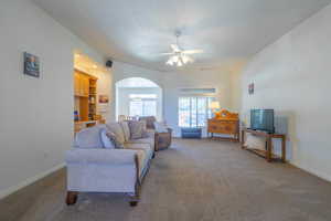 Living room featuring a ceiling fan, carpet, and arched walkways
