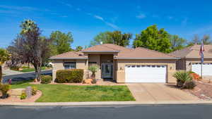 View of front facade featuring an attached garage, stucco siding, driveway, and a front yard