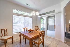 Dining space with suspended lighting, light tile patterned flooring, and a textured ceiling