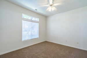Spare room featuring ceiling fan and dark carpet