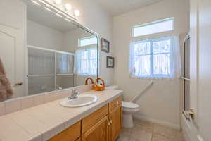 Full bathroom with vanity, light tile patterned flooring, and bath / shower combo with glass door