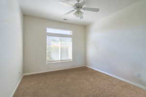 Carpeted empty room with ceiling fan and baseboards