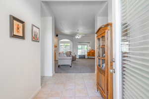 Foyer entrance with light tile patterned floors, light carpet, a ceiling fan, and arched walkways