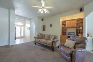 Living area featuring ceiling fan and light colored carpet